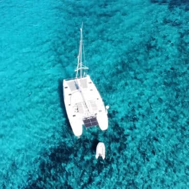 Drohnenaufnahme des Lagoon 380 S2 – Katamaran auf kristallklarem Wasser vor Sardinien.