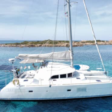 Seitenansicht des Catamaran Discovery auf Tour – Segelerlebnis in Sardinien mit Blick auf das türkisblaue Meer.