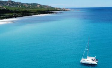 Katamaran vor dem weißen Sandstrand von Berchida in Sardinien