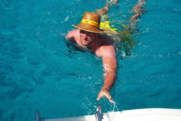 Segeltörn mit Übernachtung Gäste springen vom Katamaran ins kristallklare Wasser vor Sardinien