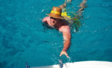 Segeltörn mit Übernachtung Gäste springen vom Katamaran ins kristallklare Wasser vor Sardinien