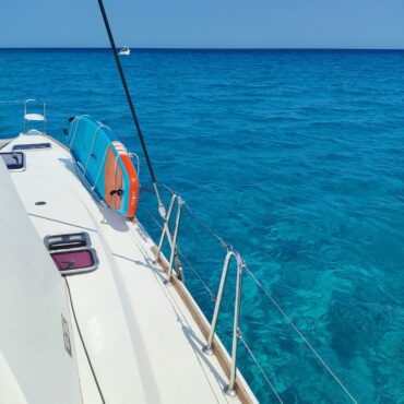 Zwei Stand-Up-Paddleboards (SUP) sind an der Reling des Katamarans Discovery befestigt, bereit für den Einsatz im blauen Meer.